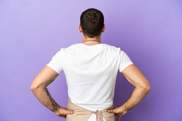 Brazilian restaurant waiter over isolated purple background in back position
