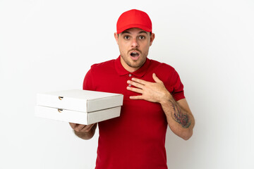 pizza delivery man with work uniform picking up pizza boxes over isolated  white wall surprised and shocked while looking right