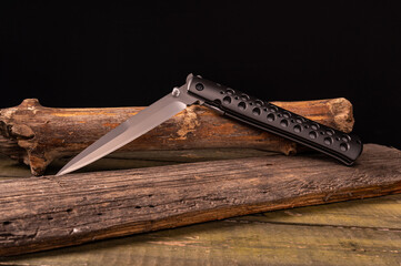 The knife is in a semi-folded position. Knife on wooden sticks.