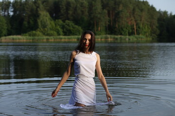 Brunette woman in white dress standing in water