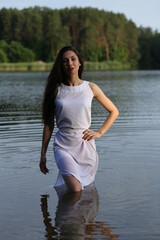 Beautiful brunette woman in white dress in the lake