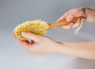 dry massage brush in hands on a grey background