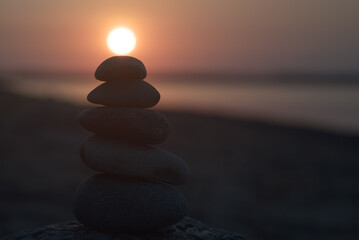 Balancing stones on top of each other. Sun at the top.