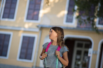 Little girl with school bag leaving school.