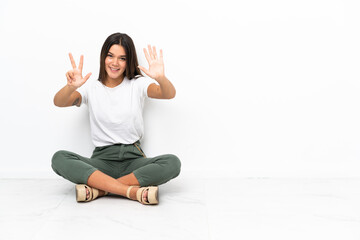 Teenager girl sitting on the floor counting eight with fingers
