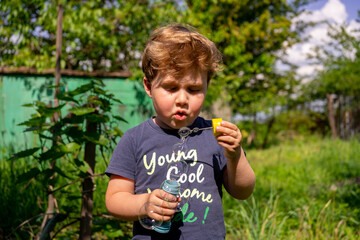 Little four years boy blow soap bubbles, outdoors, summer, happy boy
