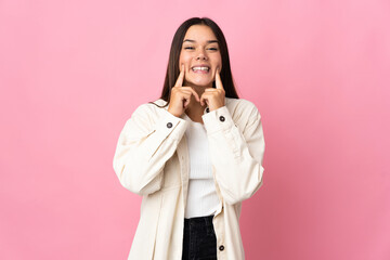 Teenager girl isolated on pink background smiling with a happy and pleasant expression