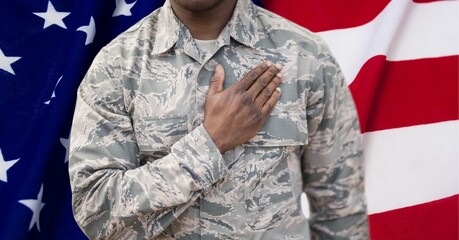 Composition of midsection of male soldier with hand on heart, against american flag