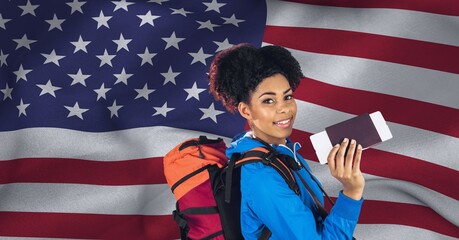 Composition of smiling woman holding passport and ticket, over waving american flag