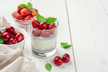 Dessert with milk, chia seeds and fresh berries and fruits on a white background. Cream pudding with strawberries and cherries.