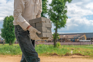 Working man has taken a lot of concrete bricks and is moving them to the right place