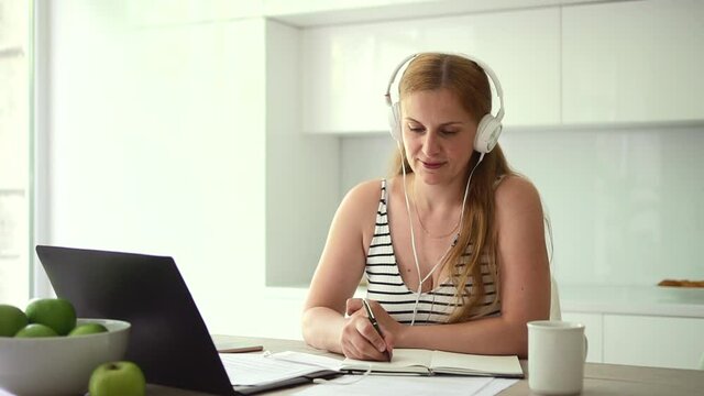 Woman in headphones writes with pen during video lecture Spbd.