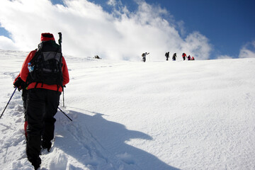 Fototapeta na wymiar Group of mountaineers walking trough the mountains covered with snow...