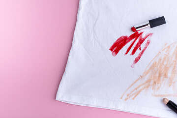 Cosmetic stain of red lipstick and foundation on clothes. isolated on pink background. top view....