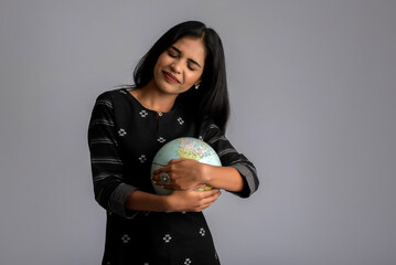 young girl holding the world globe and posing on a grey background.