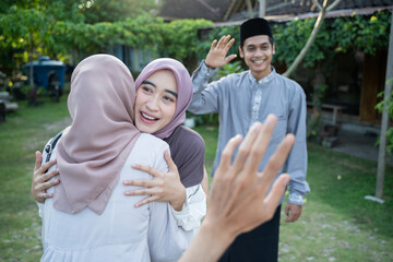 a woman wearing a headscarf hugs a female friend when meeting at a Ramadan event