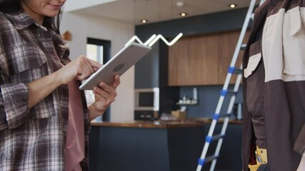 Slowmo tracking mid-section shot of young woman smiling and signing digital receipt on tablet, then shaking hands with handyman