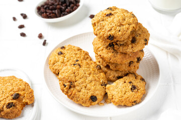 Homemade oatmeal cookies with raisins in a white plate on a light background closeup	