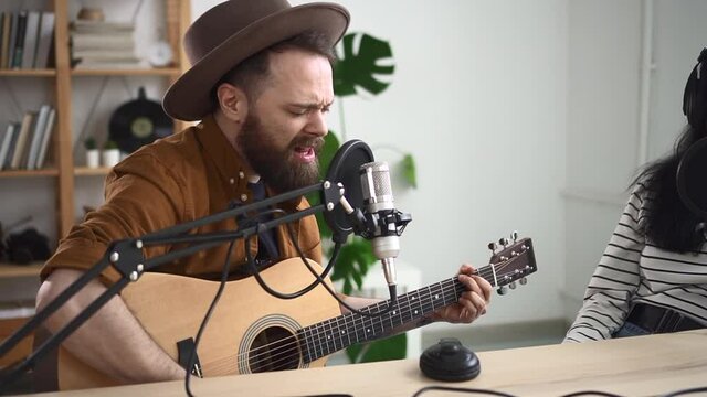 Man sing song on online radio broadcast Spbd, musician play on acoustic guitar in home recording