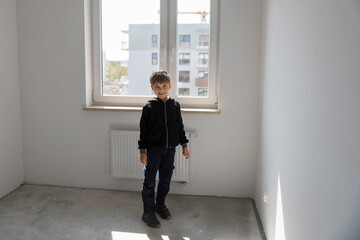 Happy young boy in his new empty room in the new flat