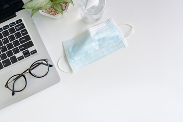 Top view of medical face mask and hand sanitizer on desk in office during the coronavirus crisis....