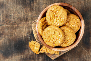 Healthy homemade oatmeal cookies with peanuts in a wooden bowl on a brown kitchen table top view with copyspace	
