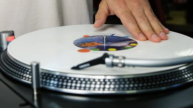 Slow motion video clip of hip hop dj scratching rare white vinyl record disc on retro turntable player device, filmed from above