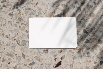 Blank business card, invitation mockup in sunlight. Terrazzo background. Marble stone texture, palm...