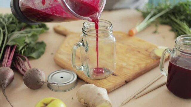 Fresh beet juice smoothie is poured into a glass jar