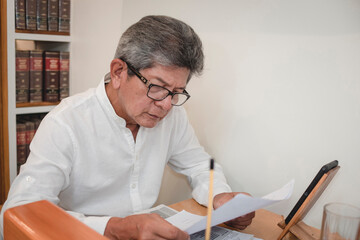 A veteran Filipino lawyer reviews some paper documents at his small office.