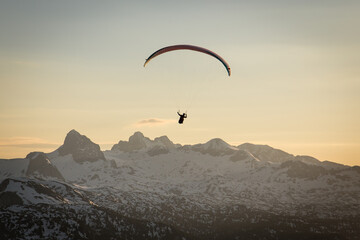 Paraglider flying in sunset over the mountains