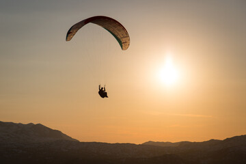 Paraglider flying in sunset over the mountains
