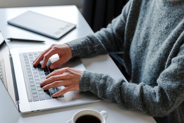 Unrecognizable female hands typing on laptop keyboard.