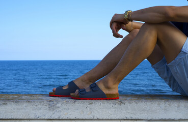 Man's legs with sandals beach scene on summer vacation - obrazy, fototapety, plakaty