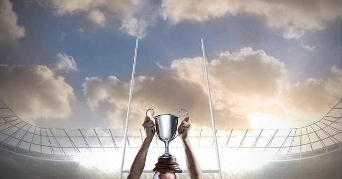 Composition of male rugby player holding cup at rugby stadium