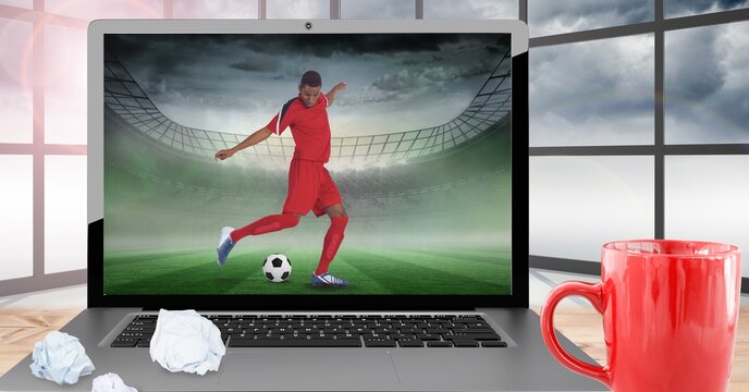 Composition of male football player kicking ball at stadium on laptop
