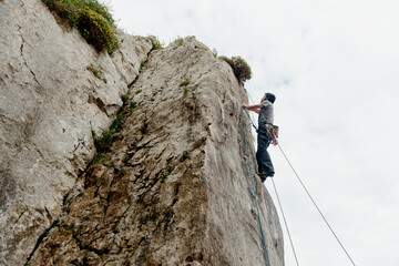 Caucasian young man climbing a rock in the mountain. mountain activity and sport