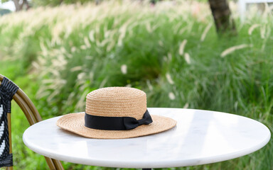 straw hat on table and chair in restaurant with outdoor garden view.