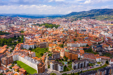 Panoramic aerial view of Oviedo city surrounded by mountain ranges on sunny summer day, Asturias, Spain