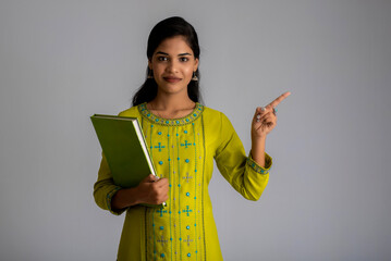Pretty young girl posing with the book on grey background