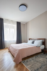 Fototapeta na wymiar double king - size wooden bed made of oak in a bright bedroom or hotel room