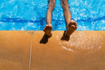 Men's legs on the edge of swimming pool