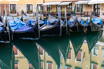 Fototapeta na wymiar Traditional Gondolas moored in a quiet Canal in the City Center of Venice, Italy on an early morning