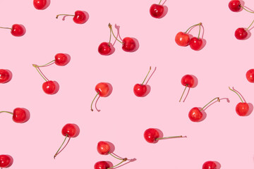 Creative pattern made with bright red cherries  on pastel pink background.  Summer fruit idea....