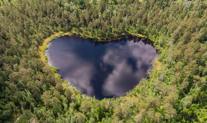 Aerial view of a heart shaped lake in a forest in Sweden during a summer day.
