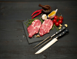 Fresh raw beef or pork steaks on stone cutting serving board