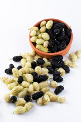 Three organic Mulberry fruits with green leaves isolated on white background.