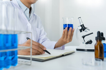 scientists researching in laboratory in white lab coat, gloves analysing, looking at test tubes sample, biotechnology concept