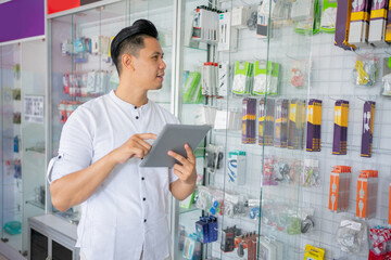 business man using a tablet with a tight stock of accessories on a glass display case on a...