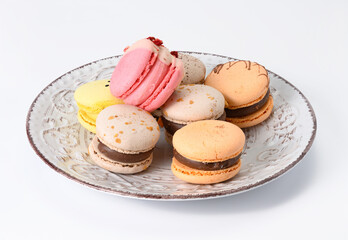 baked almond macarons on a white ceramic plate, white background